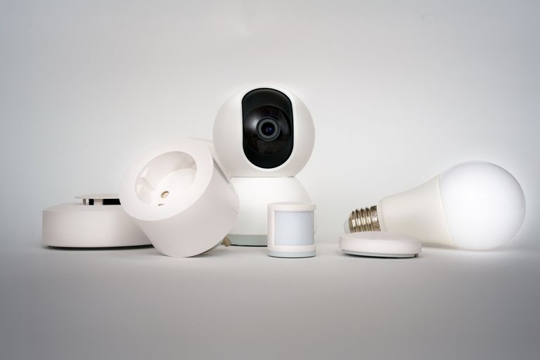 A range of smart home devices including camera and lightbulb in a minimalist setup.